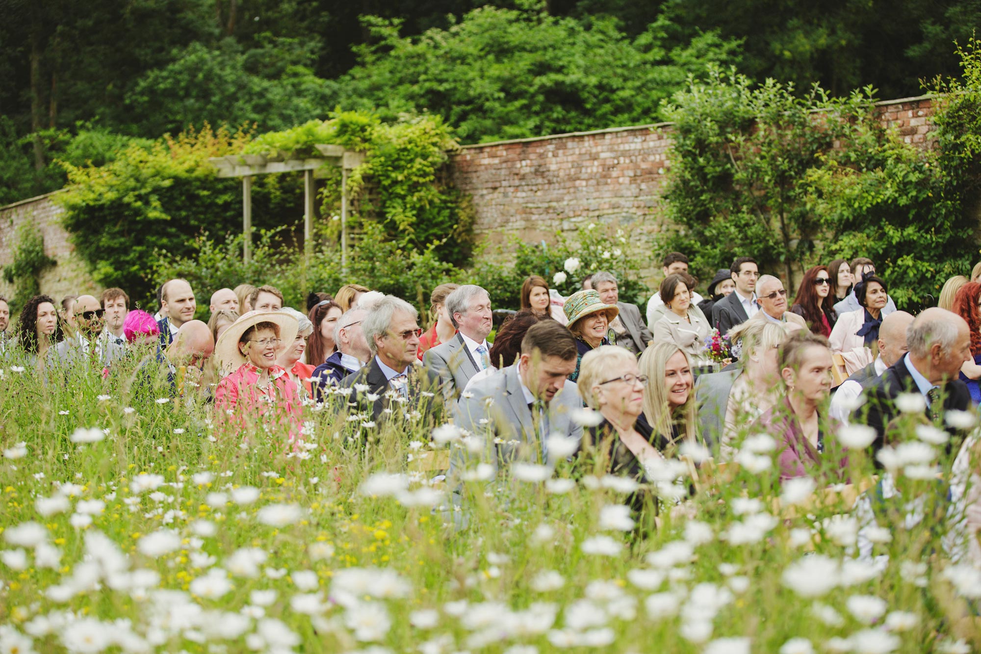 Guests seated beside wildflower meadow at Homme House outdoor wedding ceremony