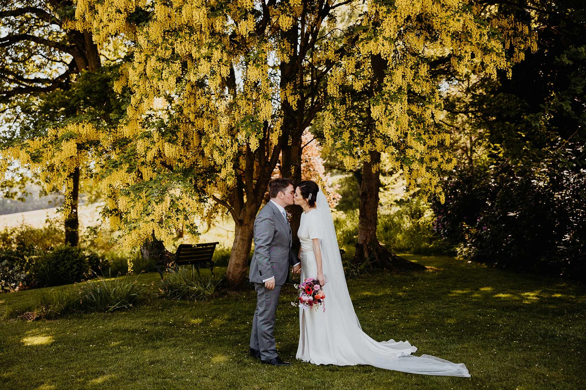 Bride-and-groom-kiss-under-Homme-House-laburnum