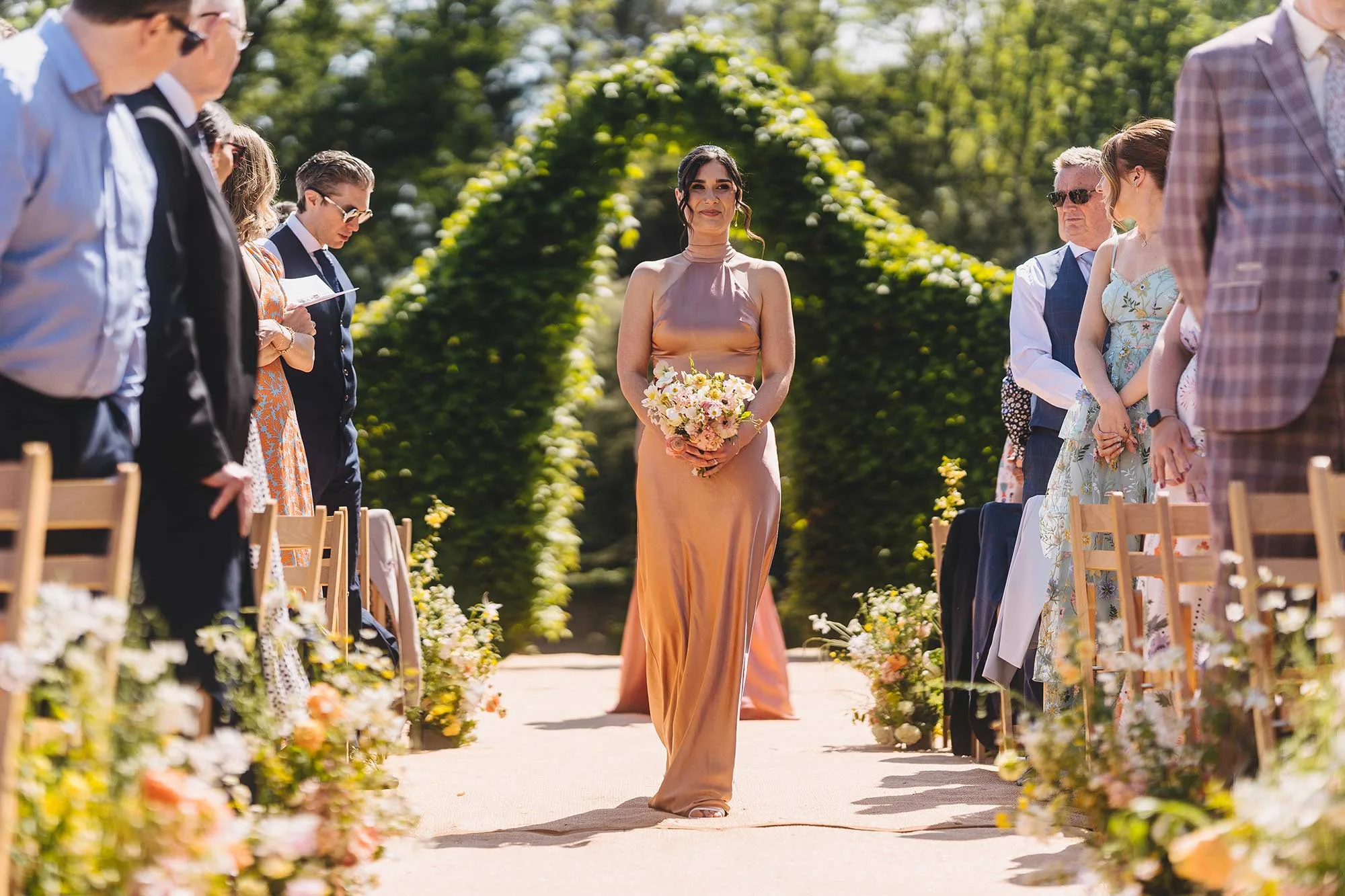 Bridesmaid-enters-outdoor-wedding-ceremony-at-Homme-House