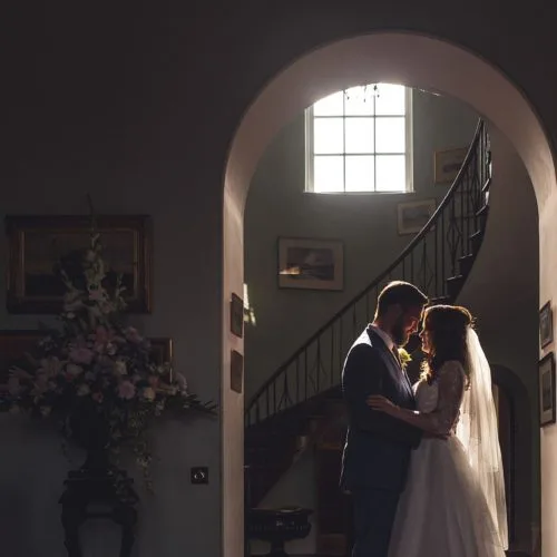 Bride and groom silhouetted in the light in the Hall at Homme House