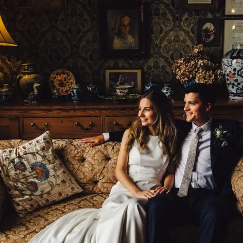 Bride and groom together on sofa in Homme House Library