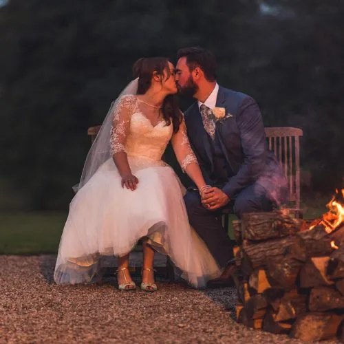 Bride and groom kiss beside firebowl at Homme House