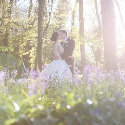 Bride and groom kissing in bluebell woodland at Homme House