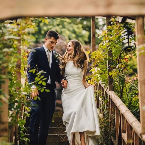 Bride and groom descending steps from the main lawn at Homme House