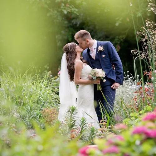Bride and groom portrait in herbaceous border at Homme House