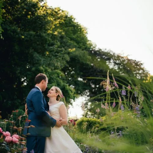 Bride and groom portrait in herbaceous border at Homme House