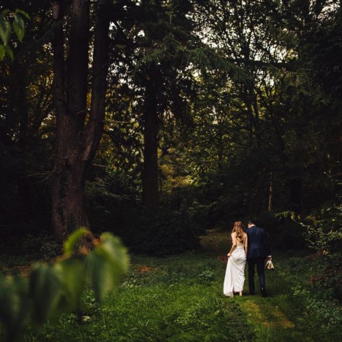 Bride and groom walking in woodland at Homme House