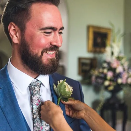 Groom having buttonhole pinned at Homme House