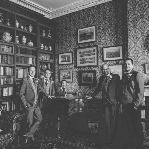 Groom and groomsmen portrait at the piano in the Library at Homme House