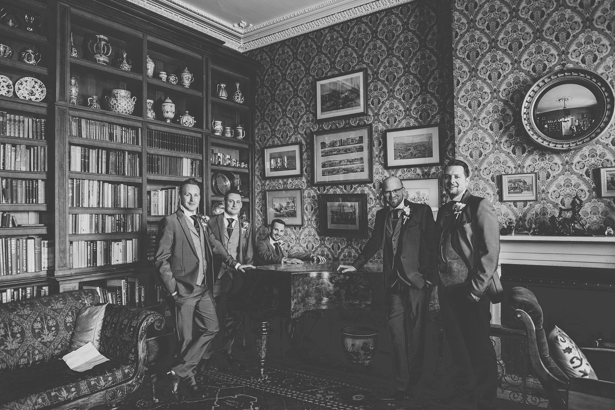 Groom and groomsmen portrait at the piano in the Library at Homme House