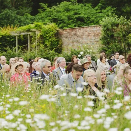 Guests seated beside wildflower meadow at Homme House outdoor wedding ceremony