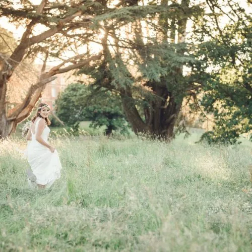 Bride in long parkland grass at Homme House in evening sunshine