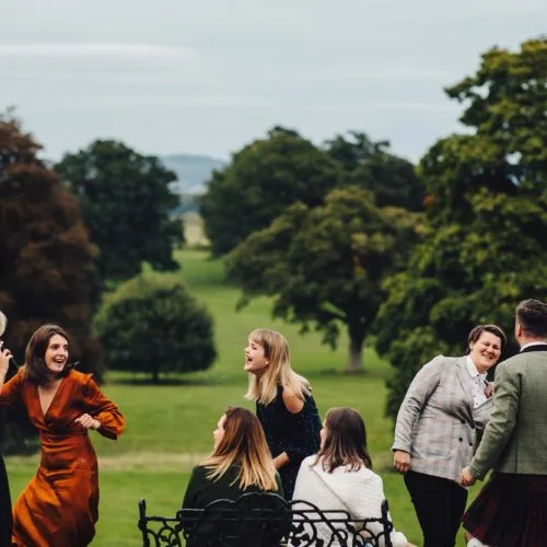 Wedding guests having fun in front of parkland at Homme House