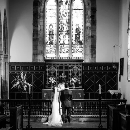 Wedding couple kneeling at altar in St. Bartholomew's Church