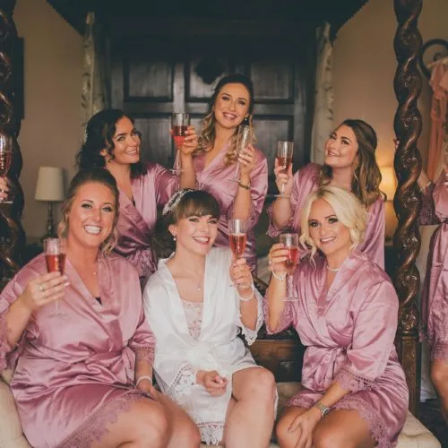 Bride and bridesmaids in dressing gowns with glasses of fizz in Homme House Bridal Suite