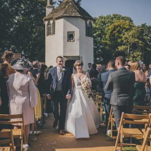 Bride and groom walking down aisle at the end of a walled garden ceremony