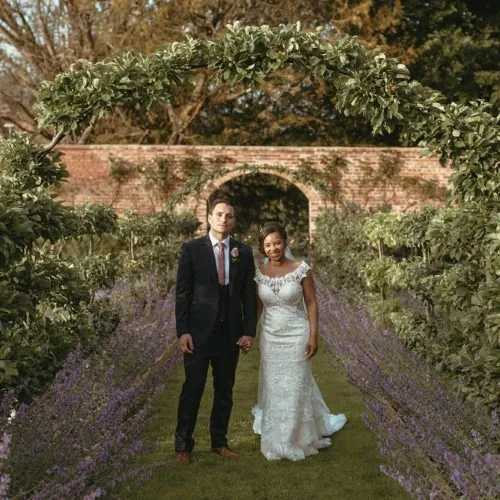 A bride and groom in the evening light on the espalier walk at Homme House