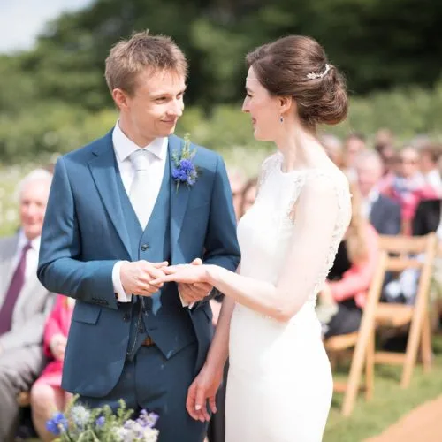 A wedding couple exchange rings at an outdoor ceremony at Homme House