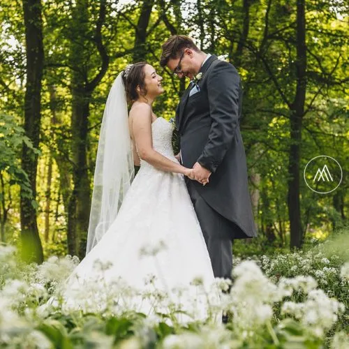 A bride and groom in the spring wild garlic in woodland at Homme House