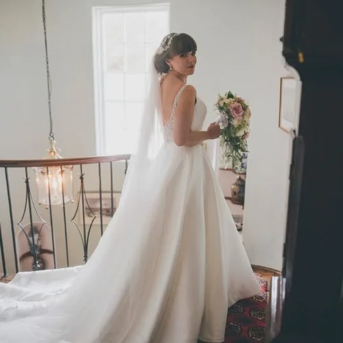 A bride looks back while waiting to descend the spiral staircase at Homme House