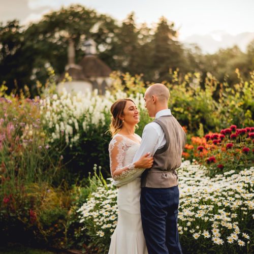 A wedding couple embrace in front of the long borders at Homme House