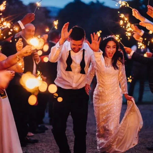 Bride and groom negotiating a sparkler tunnel outside Homme House