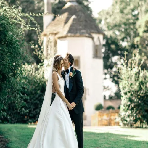 A groom kissing his bride in the Walled Garden at Homme House