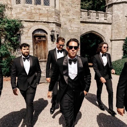 Groom and groomsmen in black tie outside the Tower wing of Homme House