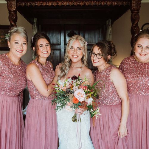 Bride-and-bridesmaids-pose-in-front-of-four-poster-bed