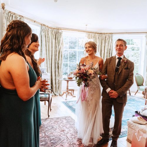 Bride-and-father-leave-Main-Suite-for-wedding-surrounded-by-bridesmaids