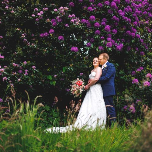 Bride-and-groom-in-front-of-rhododendrons-in-bloom-at-Homme-House