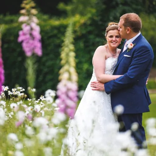Bride-and-groom-portrait-beside-walled-garden-border
