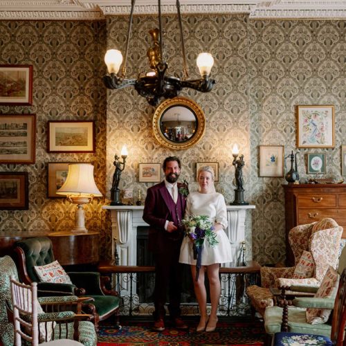 Bride-and-groom-portrait-by-mantelpiece-in-Homme-House-Library