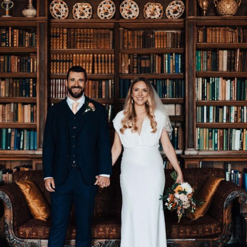 Bride-and-groom-pose-in-front-of-Homme-House-Library-bookshelf