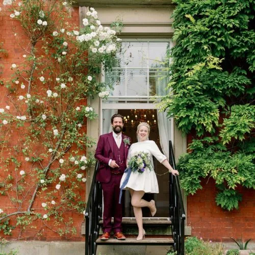 Bride-and-groom-stand-on-steps-outside-Georgian-house-window