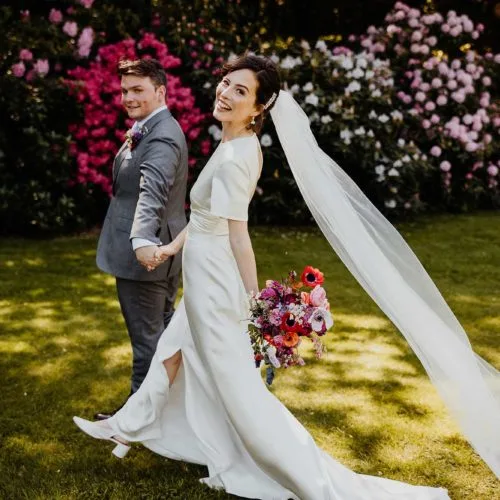 Bride-and-groom-walk-Homme-House-gardens-with-rhododendrons