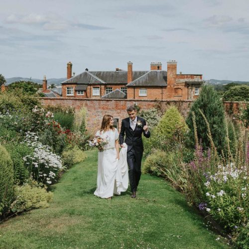Bride-and-groom-walk-up-through-Homme-House-walled-garden