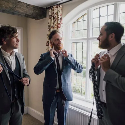 Groom-and-groomsmen-put-on-ties-in-Homme-House-Coach-House