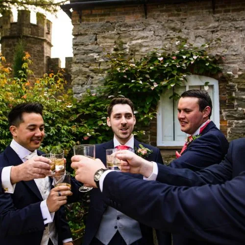 Groom-and-groomsmen-toast-in-Coach-House-courtyard-garden