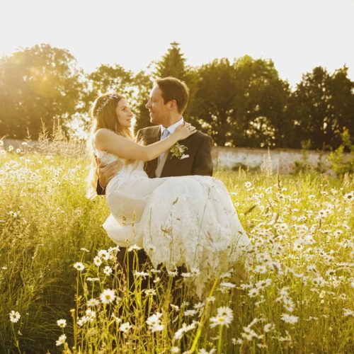 Groom-carrying-bride-in-wild-flower-meadow