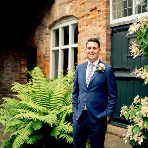 Groom-portrait-beside-ferns-outside-Coach-House