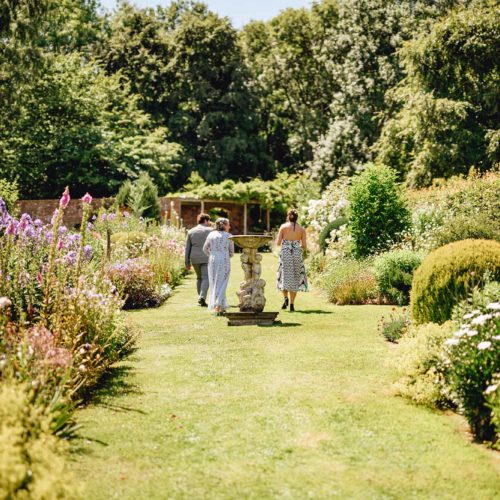 Guests-walk-up-through-Homme-House-walled-garden-for-outdoor-wedding-ceremony