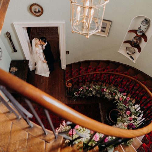 Wedding-couple-kiss-at-bottom-of-Homme-House-staircase