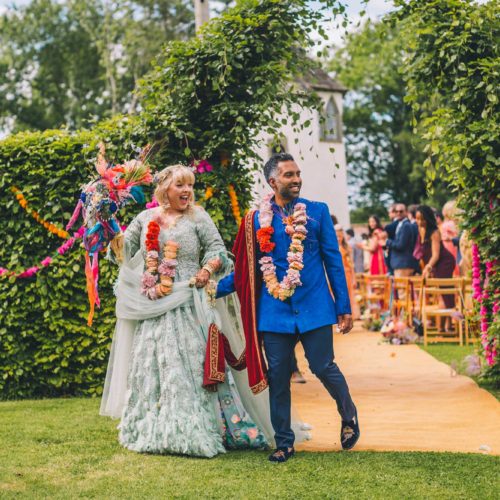 Wedding-couple-leaving-outdoor-wedding-ceremony-in-colourful-dress