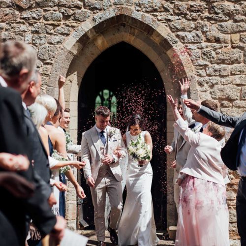 Wedding-couple-showered-with-confetti-after-St-Bartholomews-service