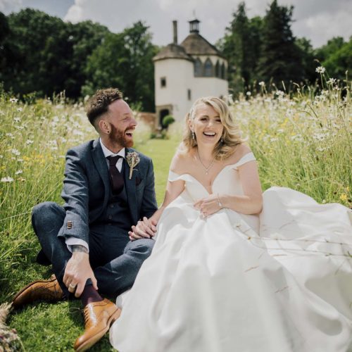 Wedding-couple-sitting-in-wild-flower-meadow-at-Homme-House