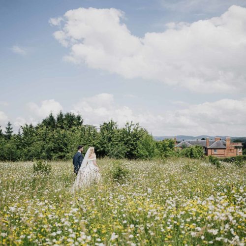 Wedding-couple-walk-through-wild-flower-meadow