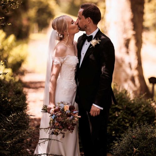 Bride-and-groom-kiss-in-dappled-woodland-shade-at-Homme-House