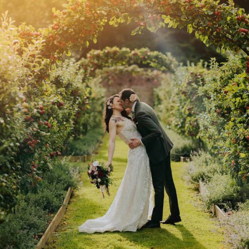 Bride-and-groom-kiss-on-the-apple-espalier-at-Homme-House
