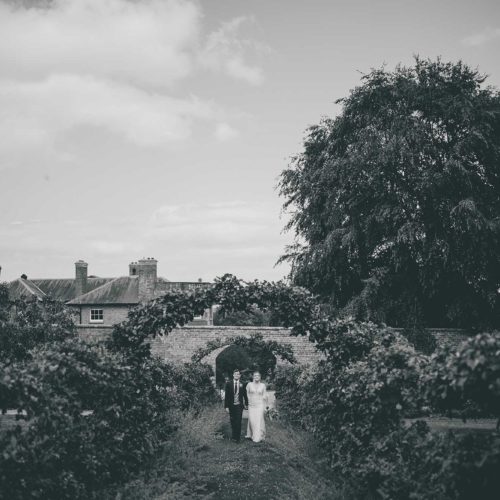Bride-and-groom-on-espaliered-apple-walkway-at-Homme-House